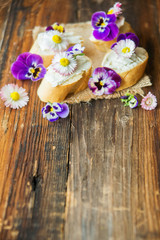 Sandwich with herb and edible flowers butter on marble cutting board. Healthy food.