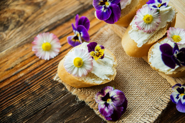 Obraz na płótnie Canvas Tasty sandwich with avocado boiled eggs, pumpkin seed and edible viola flowers in a white board. healthy food