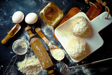 Dough with flour on an old background in a composition with kitchen accessories