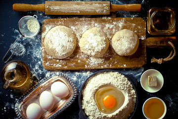 Dough with flour on an old background in a composition with kitchen accessories