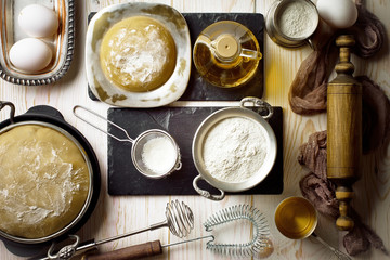 Dough with flour on an old background in a composition with kitchen accessories