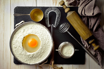 Dough with flour on an old background in a composition with kitchen accessories
