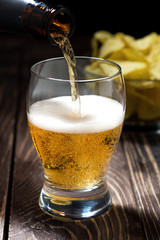 pouring beer from bottles and bowl of chips, vertical
