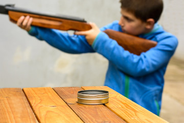 A little boy shooting from an air rifle to a target