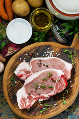 two pieces of raw pork on cutting board and ingredients, closeup top view