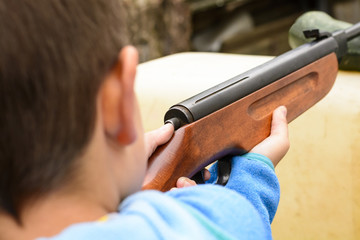A little boy shooting from an air rifle to a target