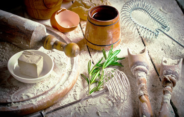 Dough with flour on an old background in a composition with kitchen accessories