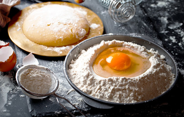Dough with flour on an old background in a composition with kitchen accessories