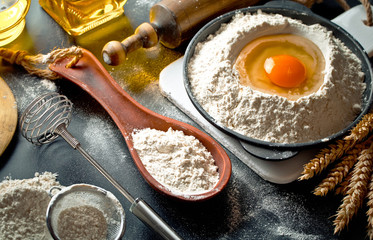 Dough with flour on an old background in a composition with kitchen accessories