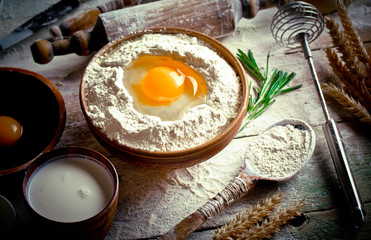 Dough with flour on an old background in a composition with kitchen accessories