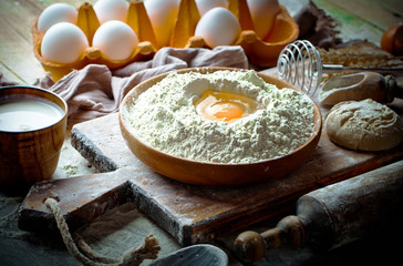 Dough with flour on an old background in a composition with kitchen accessories