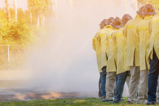 Firemen using extinguisher and water from hose for fire fighting at firefight training of insurance group. Firefighter wearing a fire suit for safety under the danger training case.