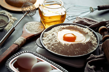 Dough with flour on an old background in a composition with kitchen accessories
