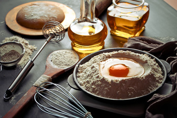 Dough with flour on an old background in a composition with kitchen accessories