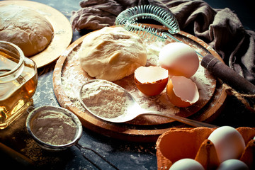 Dough with flour on an old background in a composition with kitchen accessories