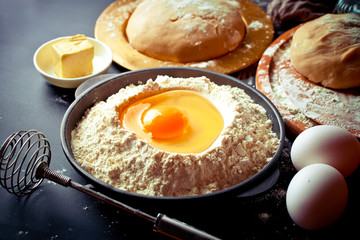 Dough with flour on an old background in a composition with kitchen accessories