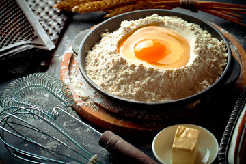 Dough with flour on an old background in a composition with kitchen accessories