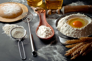 Dough with flour on an old background in a composition with kitchen accessories