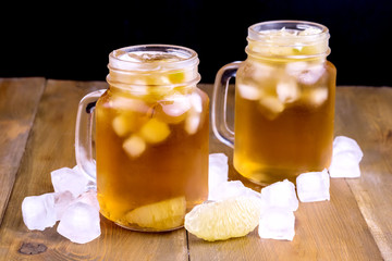Summer Cold Ice Tea with Citrus and Ice Cube in Glass Jar Wooden Background Close Up Cold Summer Beverage