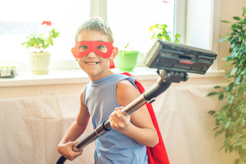 Boy child superhero costume playing is cleaning the house. Concept of children helping their parents