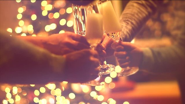 Pouring and toasting champagne. Group of people celebrating Christmas party with champagne. Glasses with sparkling wine over glowing background. Slow Motion 4K UHD video footage. 3840X2160