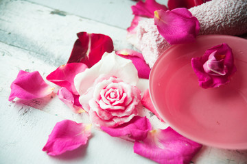 Bowl of aroma spa water with rose petals on towel, closeup