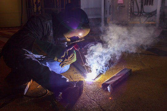 Welder perform welding to the metal plate at roof floor of manufacturing factory by using steel welding electrode in offshore oil and gas industrial operation, Blue collar jobs