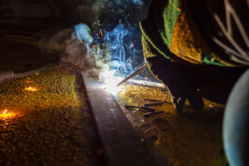 Welder perform welding to the metal plate at roof floor of manufacturing factory by using steel welding electrode in offshore oil and gas industrial operation, Blue collar jobs