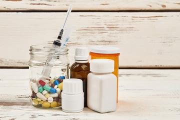Medications and syringe on wooden table. Different pills and syrups. Enhance and support immunity....