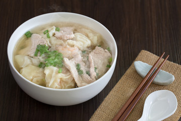 Shrimp wonton with braised pork in hot soup in white bowl on wooden table Asia food