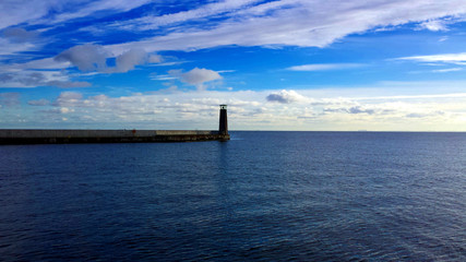 Lighthouse and breakwater between the sea and the sky