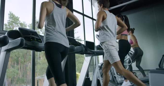 Training in a Gym/People training in a gym using treadmills and  Elliptical Cross. Training after work in the office. Caring for the health of the body. Slow motion