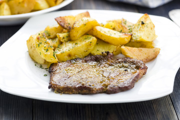 Roast pork neck served with baked potatoes.