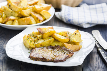Roast pork neck served with baked potatoes.