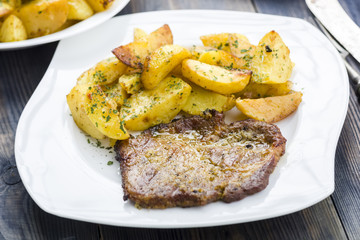 Roast pork neck served with baked potatoes.
