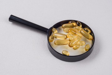 Drops for fish oil with omega 3 and vitamin D on the magnifier