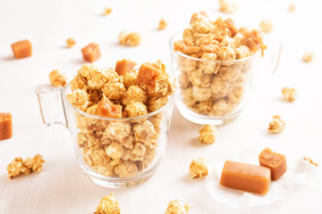Two glasses of caramel popcorn. Homemade golden sweet corn on white table