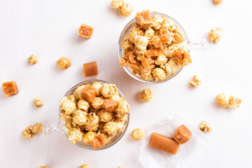 Obraz na płótnie Canvas Two glasses of caramel popcorn. Homemade golden sweet corn on white table
