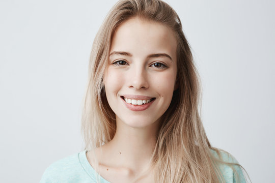 Fototapeta Pleasant-looking woman with dark eyes, beautiful lips and pure skin looking with smile at camera rejoicing her vacation, relaxing. Positive female with long blonde hair posing against gray wall