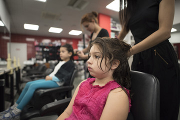 Hairdressers with little girls in beauty center saloon