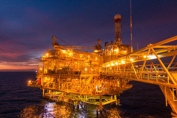 Offshore oil and gas rig platform with beautiful sunset time or twilight time in the gulf of Thailand for business industrial concept