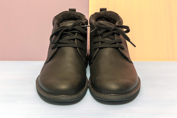 Men's, leather shoes. Pair of men's, winter boots of black color with laces on a color background.