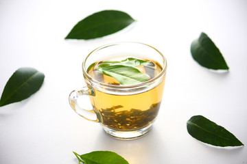 A glass of tea leaves green on a white background.