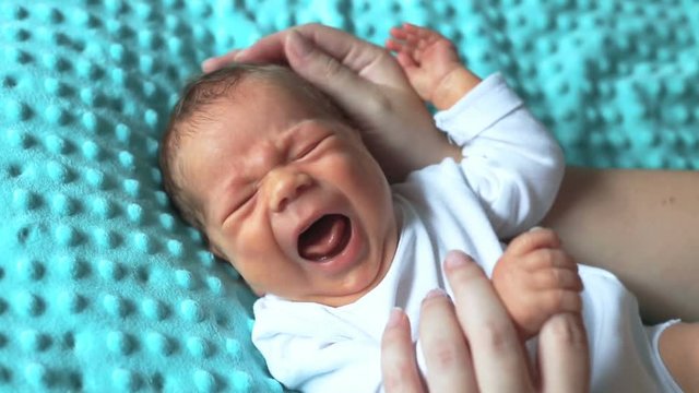 Mother strokes her little baby to calm him down while crying
