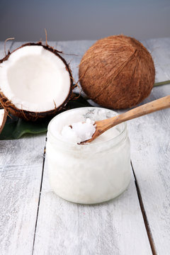 coconut and opened glass jar with fresh coconut oil on wooden background.