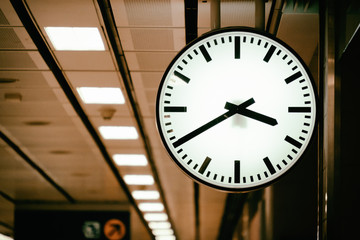 Sepia tone picture of retro white Clock in public train station platform.