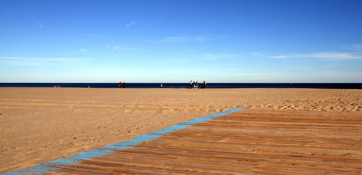 Menschenleerer Strand von Valencia vor blauem Himmel