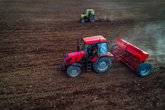 Tilt shift of aerial view of tractors working on the harvest field