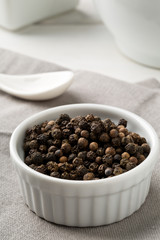 Fototapeta na wymiar Raw, natural, unprocessed black pepper peppercorns in white bowl
