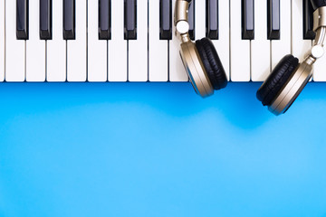 Music keyboard with golden headphone for blue copy space below